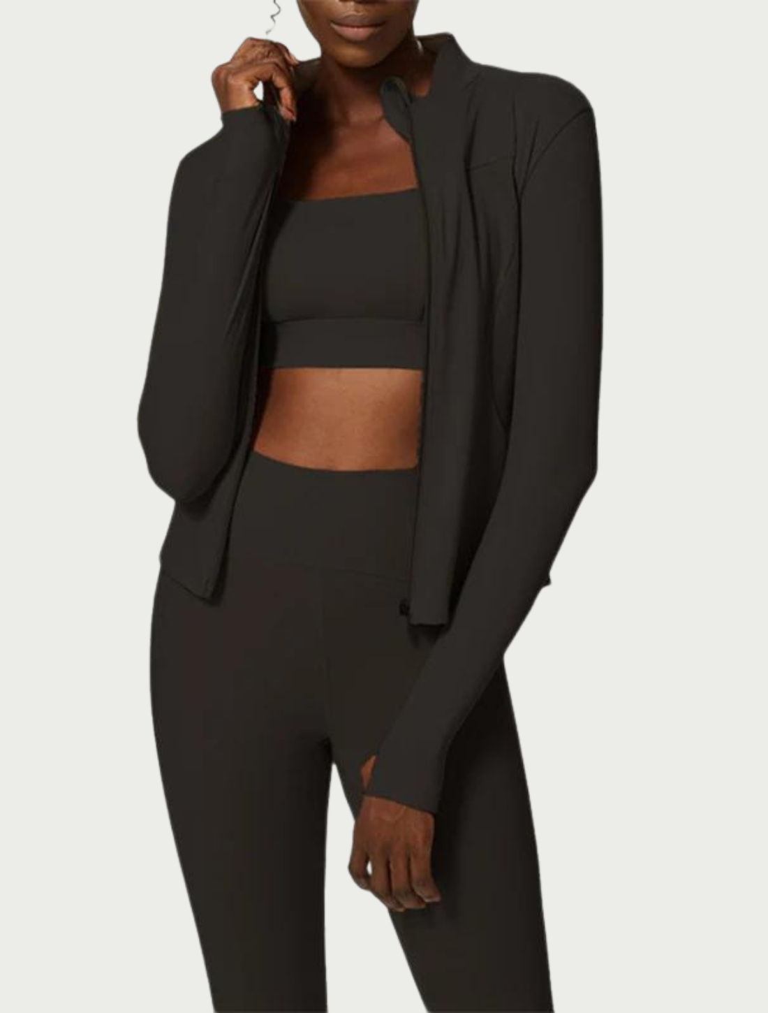 Conjunto fitness preto composto por top esportivo, calça legging de cintura alta e jaqueta leve de mangas longas, ideal para treinos ou atividades ao ar livre com estilo e conforto.