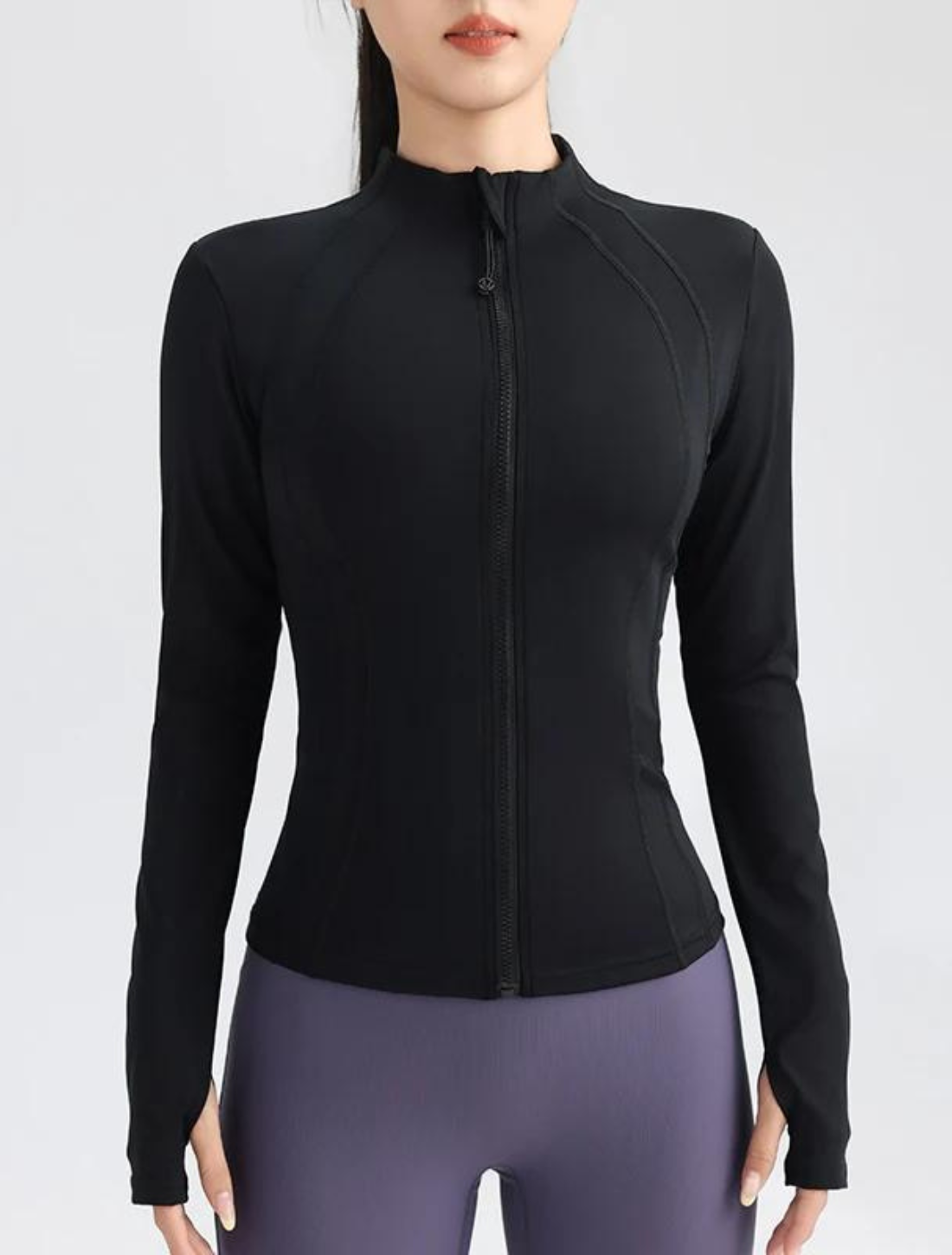 Mulher vestindo uma jaqueta fitness preta com zíper frontal e design ajustado que valoriza a silhueta. Ideal para treinos, com tecido elástico e respirável.
