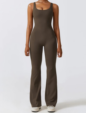Mulher vestindo um macacão fitness marrom de tecido ajustado e confortável, com design de alças largas, pernas alongadas e corte elegante, ideal para atividades físicas ou casual.